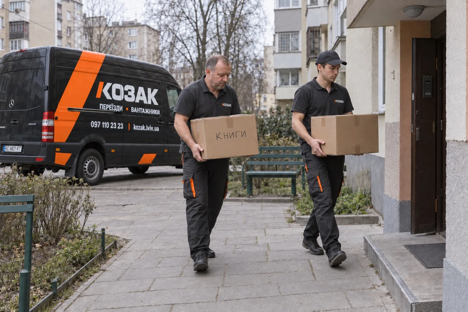 Вантажники несуть коробки до під’їзду поруч із бусом Козака